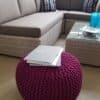 Rosa stickpuff i modern vardagsrum med soffa och bord.