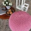 Rosa stickad sittpuff på uteplatsen med dekorationer.