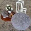 Stilren sittpall med stickad yta, blomsterarrangemang och ljuslyktor.