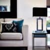 Modern svart lampbord bredvid beige soffan med kuddar i vardagsrummet.