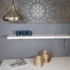 Modern metallampel i guld hänger i vardagsrum med dekorativa vaser.