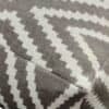 Detaljerad bild av textilmatta med beige och vit geometrisk design.