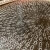 Detaljerad bild av en rund guldfärgad bricka med textur.