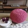 Stor rosa stickpall pouf som sittplats och dekorativt inslag i vardagsrummet.