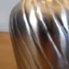 Detaljerad bild av metallvas med gulddetaljer för inredning.