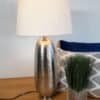 Elegant bordslampa med silverfärgad metallbas och vit lampskärm.