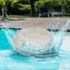 Poolkudde som flyter i poolen med vatten som sprutar ut.