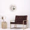 Elegant metall sidobord i guld med rund spegel och växt i modern inredning.