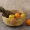 Trådbunden fruktskål med ananas, äpplen och apelsiner.