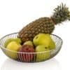 Frukt i rund metallkorg med ananas och äpplen.