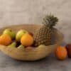 Träfruktskål med äpplen, apelsiner och ananas.