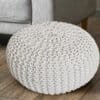Grovt stickad sittpuff i off-white färg för hemmet.