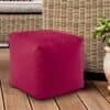 Mörkröd sittpuff i tyg på trädäck med växter och möbler.