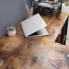 Träbord med laptop, växt och kontorsmaterial i rustik design.