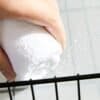 Person torkar glasruta med vit mikrofibertrasa, vattenstänk syns.