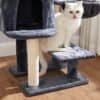 Vit katt på grått kattträd i hemmet.