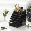 Stapelbar sminklåda i svart med makeup- och kosmetikaprodukter.
