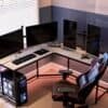 Hörn-setup med tre skärmar, gamingstol och dator för hemkontor.