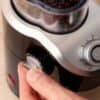 Närbild av hand som justerar en elektrisk kaffekvarn.