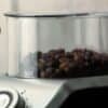 Elektrisk kaffekvarn med transparent behållare och 100g kapacitet.