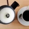 Mjölkskummare och kaffe på träbord för perfekt cappuccino.