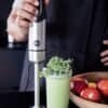 Handblender Eldom BL210 mixar en grön smoothie i ett glas.