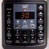 Elektrisk multicooker kontrollpanel med digital display och knappar.