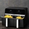 Svart dubbel airfryer med pommes frites, modern design och digital kontrollpanel.