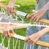 Personer monterar hammock med handlanu.se tillbehör i trädgården.