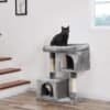 Kattklätterställning med två grottor och svart katt på toppen.