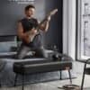 Musiker spelar elgitarr i modern sovrumsmiljö.