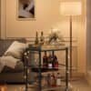 Köksvagn med tre hyllor, flaskor och dekorationer i vardagsrum.