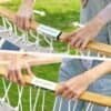 Personer monterar en hammock med HandlaNu.se logotyp för utomhusbruk.