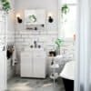 Elegant white bathroom with black fixtures and green plants.